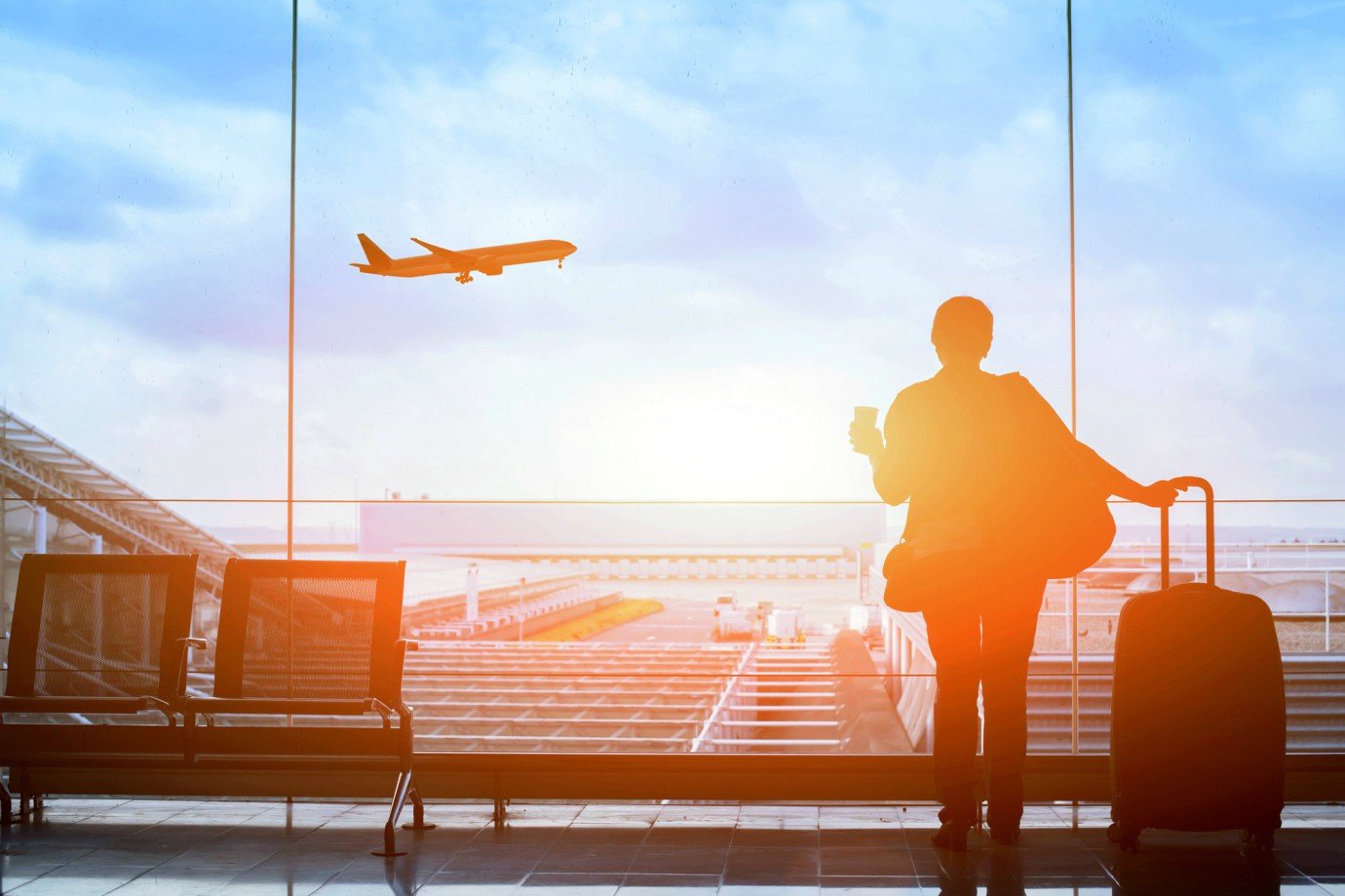 Imagem de um viajante no aeroporto observando um avião